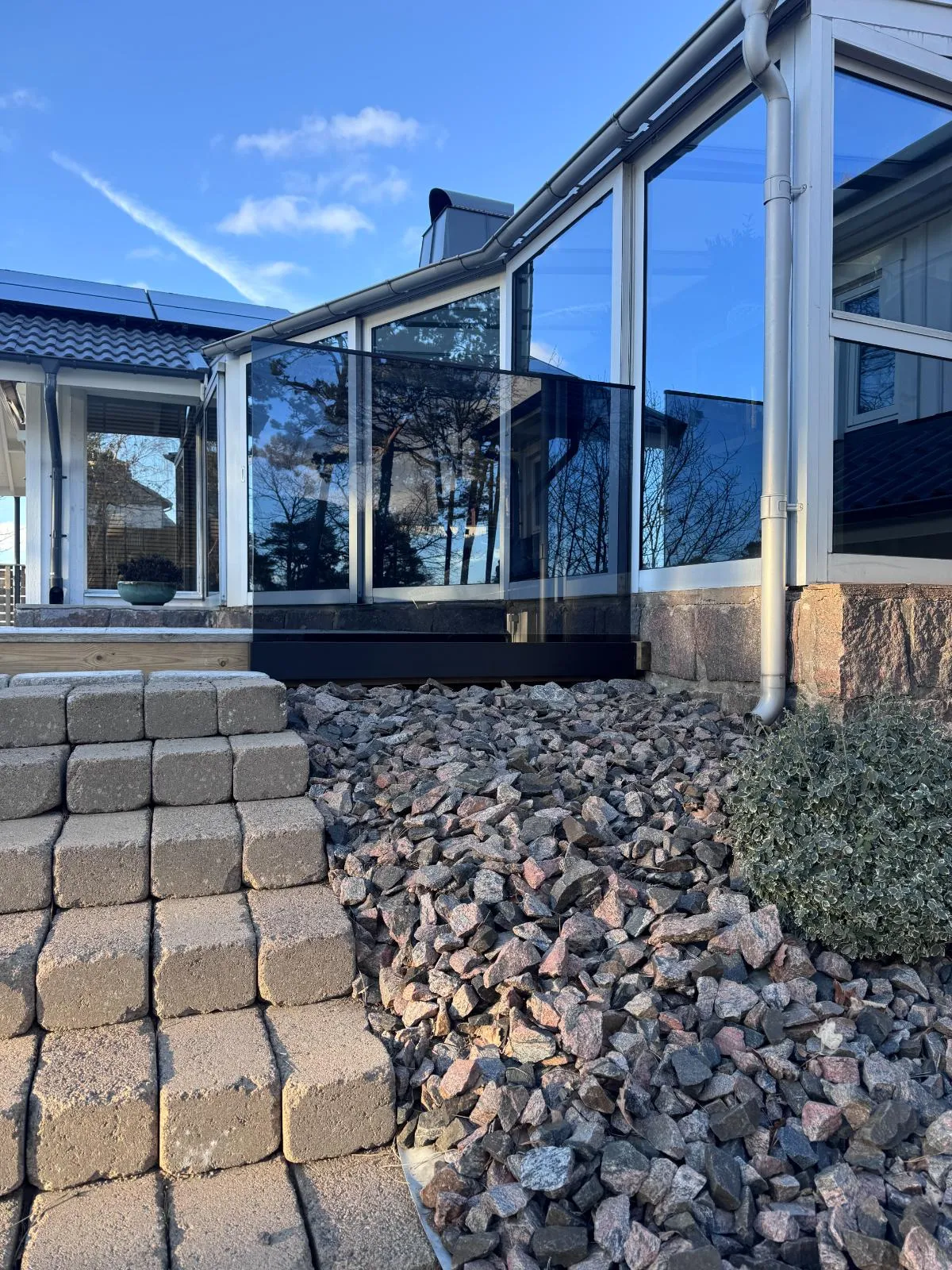 Sidomonterat glasräcke med profil vid trappa i trädgård