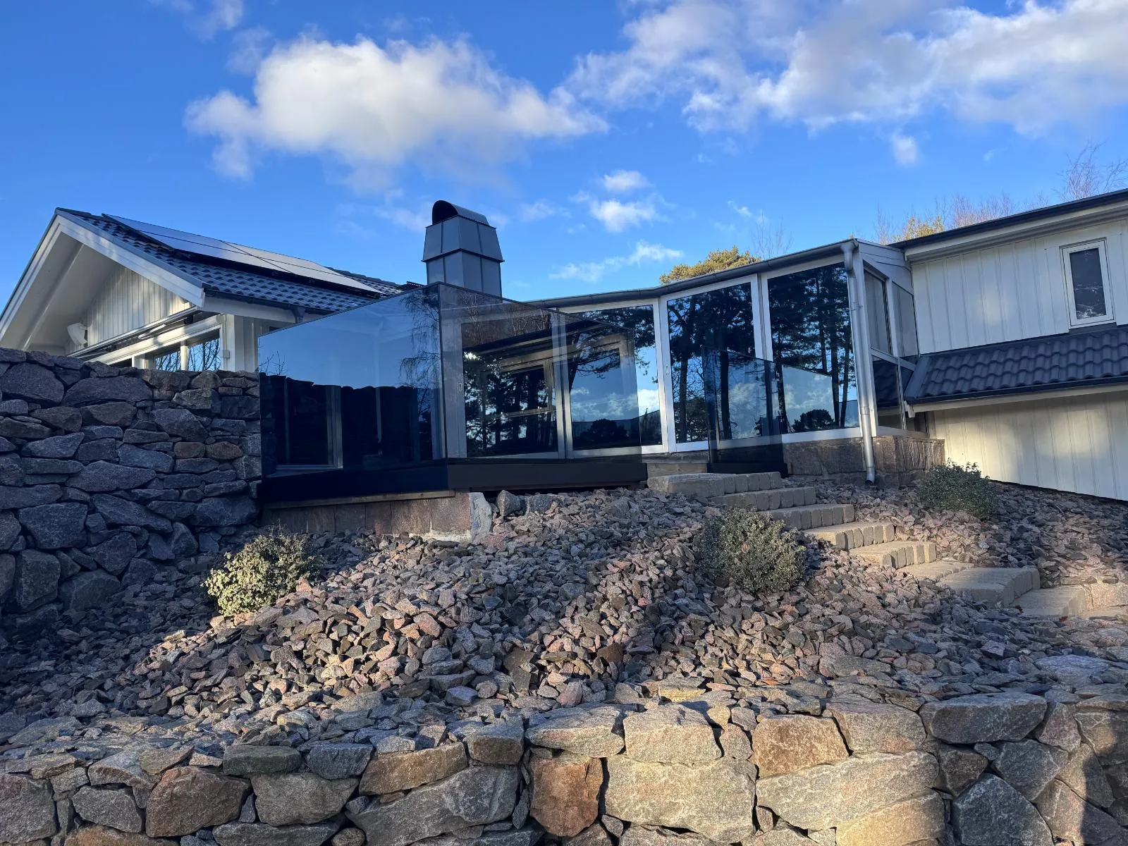 Sidomonterad helglasprofil med tonat glas ovanför stenmur