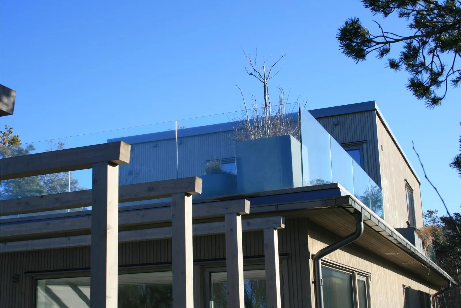 Modernt hus med glasräcke och pergola