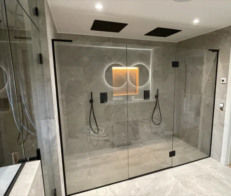 Lyxigt badrum med glasvägg och svarta beslag